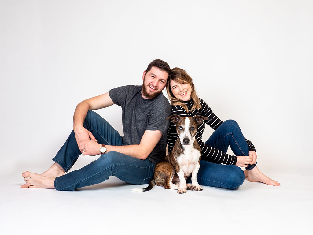 couple sitting on floor laughing with their dog taken by pet photographer in Braintree